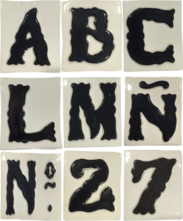 Letras y números en azulejos blancos y relieve negro.